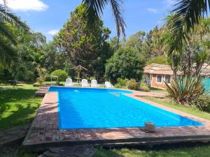 a swimming pool in a yard with two lawn chairs at El Campito in Abasto