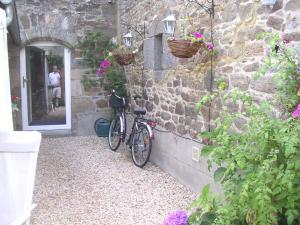a bike parked next to a stone wall with flowers at Chambre d'hôte Priory-View Dinan in Dinan