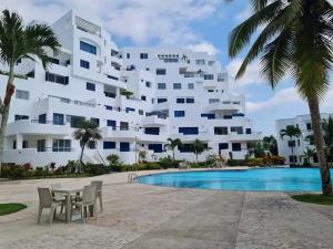 a large white building with a table and chairs next to a swimming pool at Exclusivo Departamento playa in Same