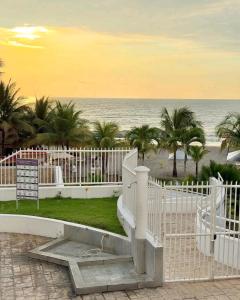 a white fence next to the ocean with palm trees at Exclusivo Departamento playa in Same