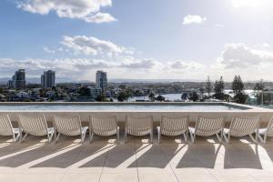 a row of chairs sitting on a patio with a pool at Bounce Surfers in Gold Coast