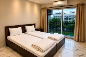 two beds in a room with a large window at ASPA Apartments in Navi Mumbai