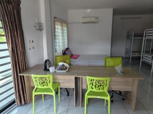 a dining room with a wooden table and two green chairs at Sun Flower Guest House 17mins to Ipoh Town in Ipoh