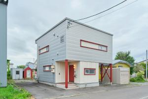 a gray house with a red door at Suzuran Haus in Higashikawa