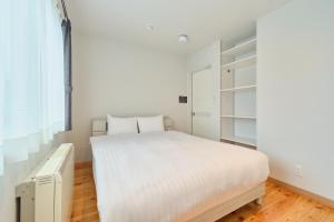 a white bedroom with a bed and a closet at Suzuran Haus in Higashikawa