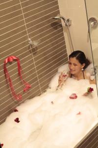 a woman sitting in a bath tub with a glass of wine at Business Class Prims Hotel in Jaén +41 photos