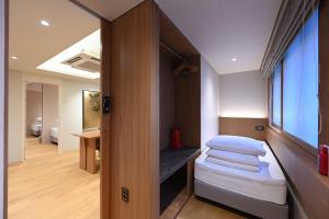 a small room with a bed and a window at 한 스위트 서울 in Seoul