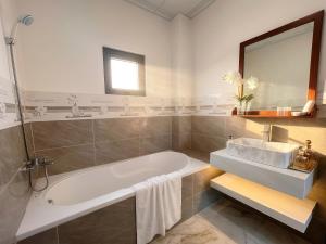 a white bathroom with a tub and a sink at Mimosa 8 Hotel - Ninh Chử in Ninh Hải