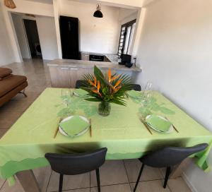 a green table with chairs and a vase of flowers on it at Fare Manihinihi 2BR APPARTMENT TARAVAO CENTER in Mitirapa +4 photos