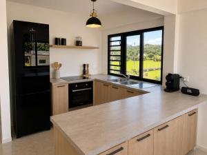 a kitchen with a black refrigerator and a counter top at Fare Manihinihi 2BR APPARTMENT TARAVAO CENTER in Mitirapa
