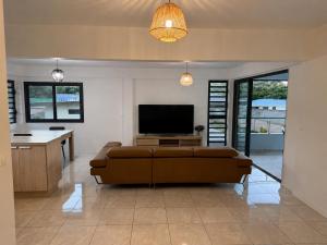 a living room with a couch and a flat screen tv at Fare Manihinihi 2BR APPARTMENT TARAVAO CENTER in Mitirapa