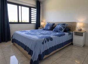 a bedroom with a bed with a blue comforter at Fare Manihinihi 2BR APPARTMENT TARAVAO CENTER in Mitirapa