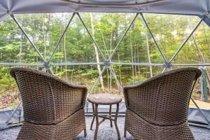 two chairs and a table in a glass house at Pleasant River Glamping Dome 3 King bed in Bethel