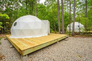 a tent sitting on a wooden platform in the woods at Pleasant River Glamping Dome 3 King bed in Bethel