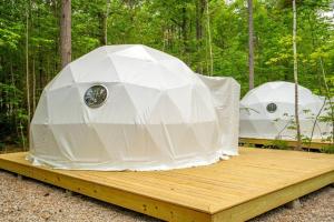 two yurt tents on a wooden platform in the woods at Pleasant River Glamping Dome 3 King bed in Bethel