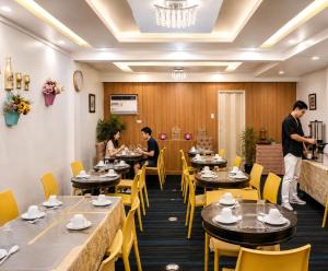 a restaurant with tables and yellow chairs and people in it at Amax Inn Makati in Manila