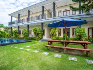 a picnic table with an umbrella in front of a building at Pondok Lulik Homestay Canggu in Canggu