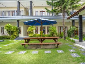 a picnic table with an umbrella in a yard at Pondok Lulik Homestay Canggu in Canggu