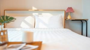 a bedroom with a white bed and a lamp on a table at Goseong Araenmaru Pension in Goseong