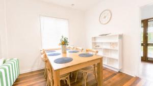 a dining room table with chairs and a clock on the wall at Teke Cottage in Wooli