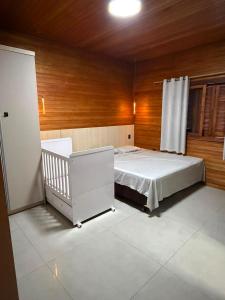 a bedroom with a white bed and a wooden wall at Chalé Rossa in Xangri-lá +26 photos