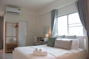 a white bedroom with a large bed with two towels on it at 95 Lodge in Bangkok