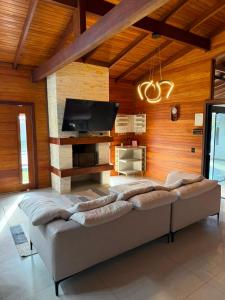 a living room with a couch and a flat screen tv at Chalé Rossa in Xangri-lá