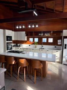 a kitchen with a large white island with bar stools at Chalé Rossa in Xangri-lá
