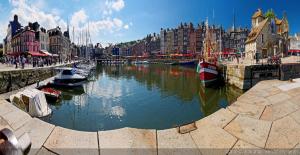 une rivière avec des bateaux dans une ville avec des bâtiments dans l'établissement Le Central, à Honfleur