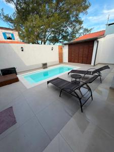 a swimming pool with two chairs and a table at Chalé Rossa in Xangri-lá