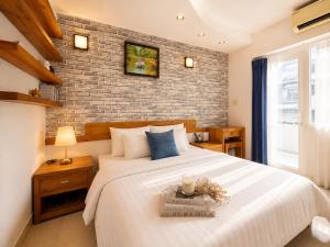 a bedroom with a large white bed with a brick wall at Saigon Quiet Stay in Ho Chi Minh City
