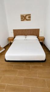 a white bed in a room with wooden floors at Origen&Madera in Alcalá del Júcar