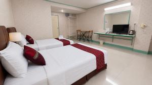 a hotel room with two beds and a television at Happyland Mansion in Bangkok
