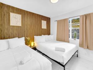 two white beds in a room with a window at Casa Playa Coastal Comfort 10 Min From Beach in Hallandale Beach