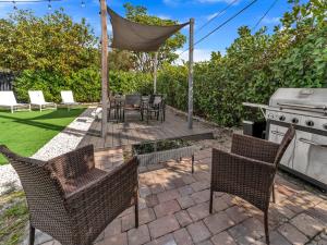 a patio with a grill and chairs and a table at Casa Playa Coastal Comfort 10 Min From Beach in Hallandale Beach