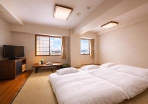 a bedroom with two beds and a flat screen tv at Hotel Airport Komatsu in Komatsu