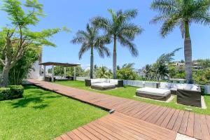 a garden with two benches and palm trees at Magia Multi Listings in Playa del Carmen