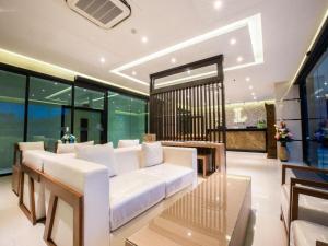 a living room with a white couch and some windows at L Hotel in Ban Si Than
