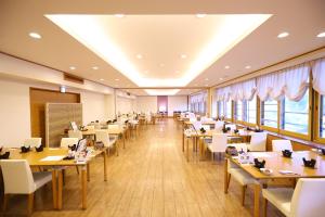 a dining room with tables and chairs and windows at Yugawara Chiyodasou in Yugawara
