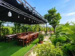 a restaurant with wooden tables and chairs under a canopy at Daisy's Villa TamCoc in Ninh Binh