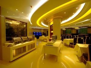 a restaurant with tables and chairs and a yellow ceiling at Changchun Global Hotel in Changchun