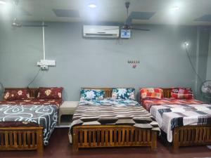 two beds and a couch in a room at Maha Periyava Kuteeram 10 Adults Budget Stay in Kumbakonam