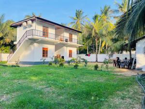 a white house with palm trees in the background at Nachchi Beach Sweet Stay in Nilaveli