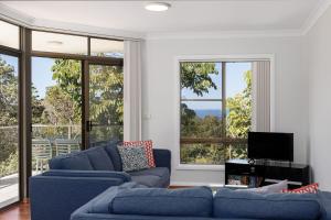 a living room with two blue couches and large windows at Ocean Retreat in Nambucca Heads
