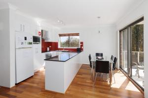 a kitchen with white appliances and a table with chairs at Ocean Retreat in Nambucca Heads