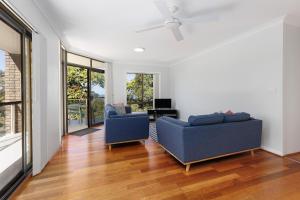 a living room with two blue couches and a television at Ocean Retreat in Nambucca Heads +9 photos