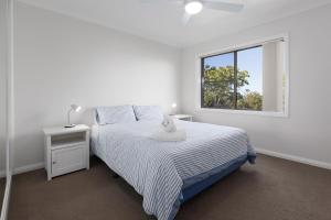 a white bedroom with a bed and a window at Ocean Retreat in Nambucca Heads