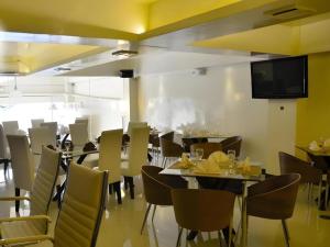 a restaurant with tables and chairs and a flat screen tv at The Grande Suites in Surigao