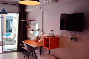 a living room with a table and a television on a wall at Z2 Boutique Hotel in Ban Samet