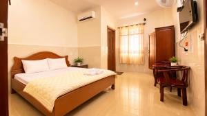 a bedroom with a bed and a desk and a television at HOTEL HOA LU Buôn Ma Thuột in Buôn Kô Sir